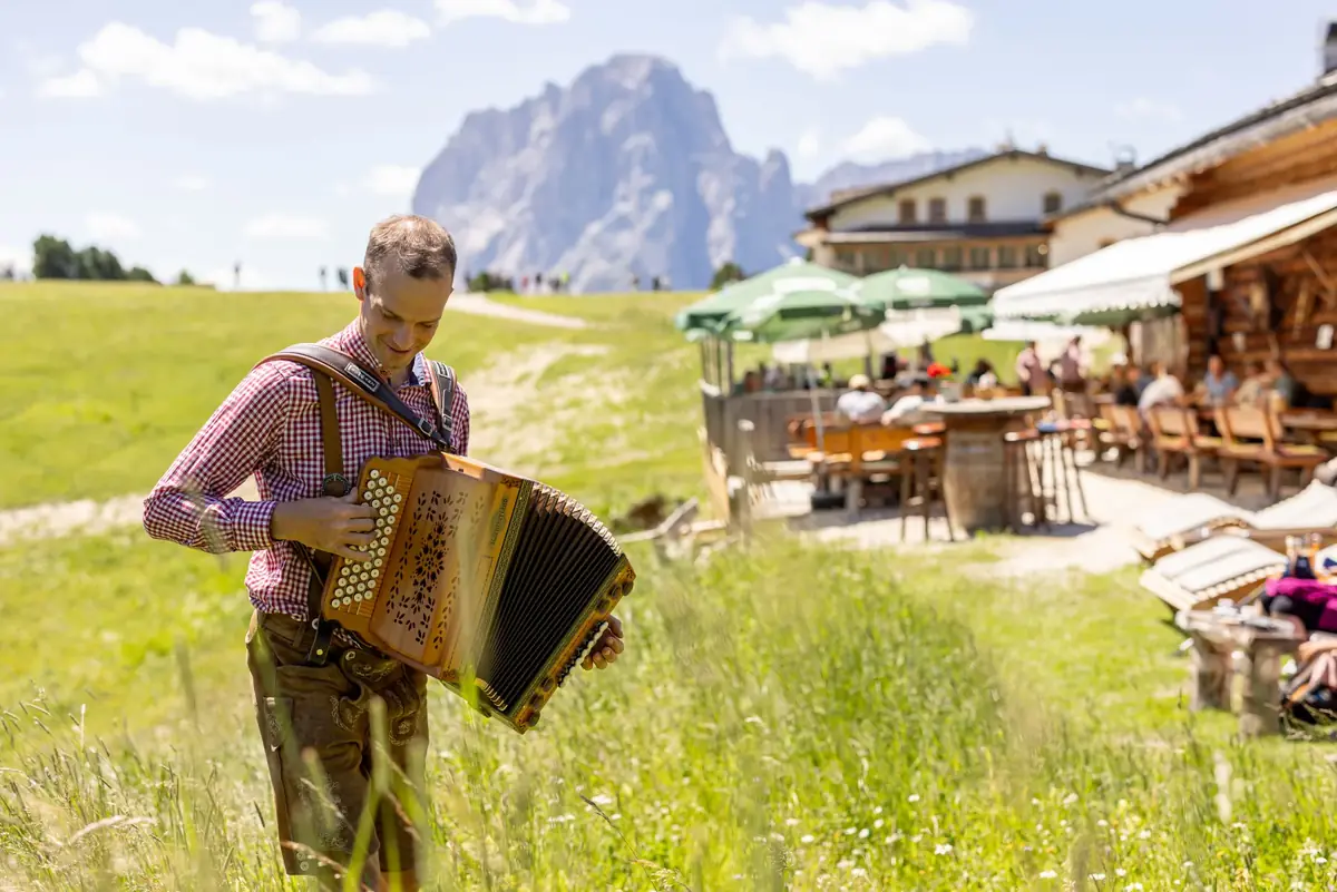 Musikant mit Ziehharmonika vor der Baita Odles
